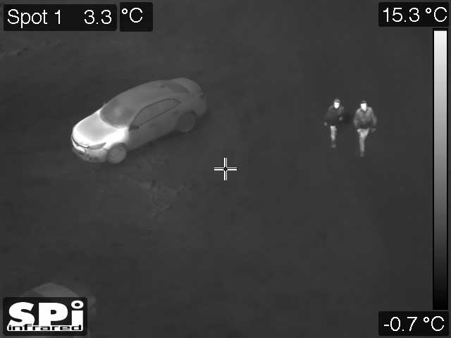 white hot thermal image of people walking away from their car